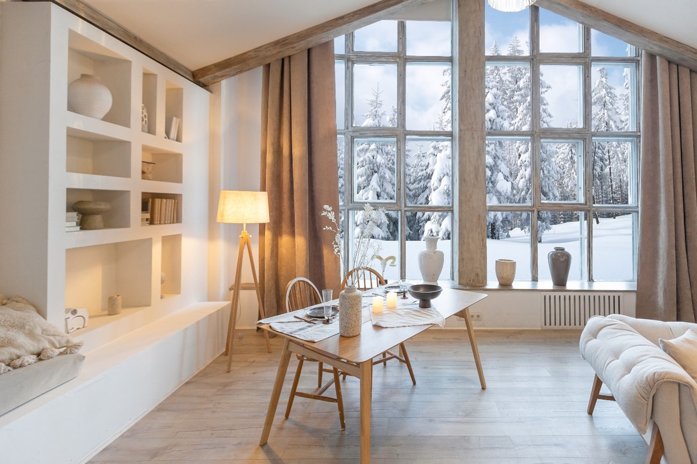 A view of a sitting room with white and beige furniture. There are two large windows letting in winter's bright light.