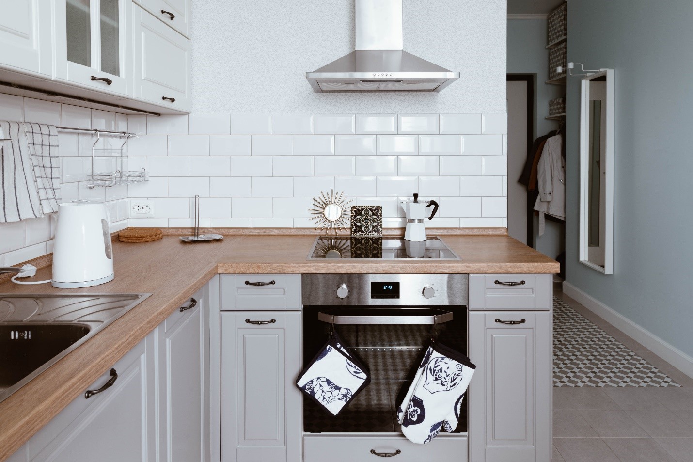 A bright kitchen with a white backsplash and decorated stove.