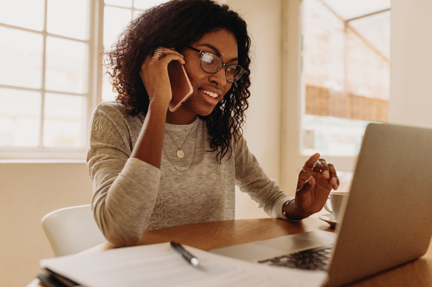 A woman looking at her computer as she speaks on the phone.