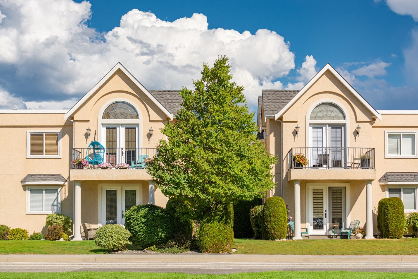 Well maintained town houses on a sunny day with big, warm clouds.