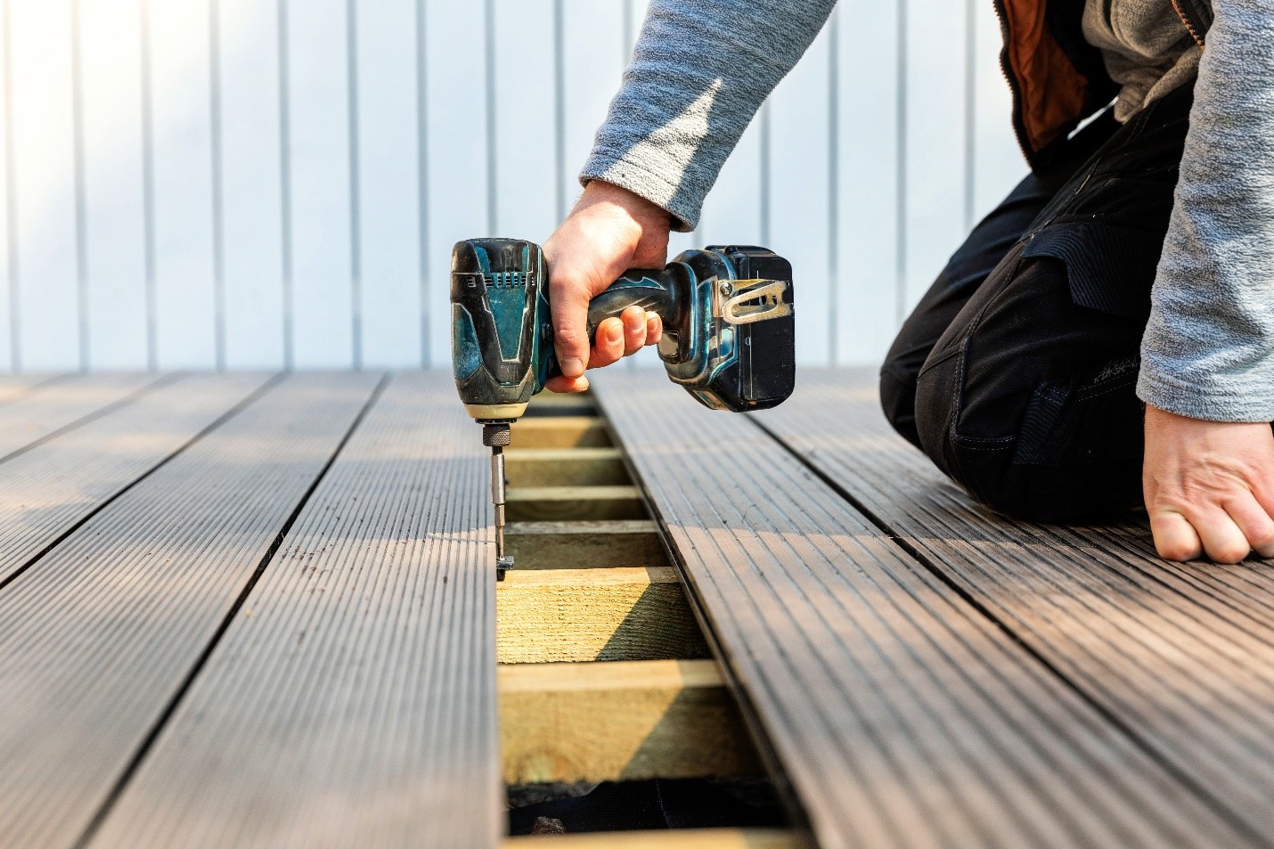 A close up shot of someone drilling screws into their deck.