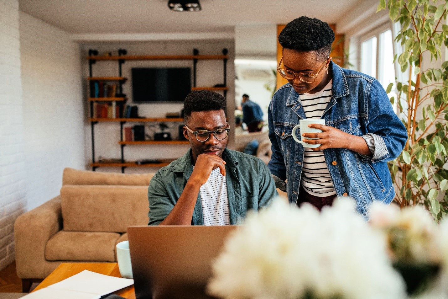 Two people wearing glasses and looking thoughtfully at a laptop.