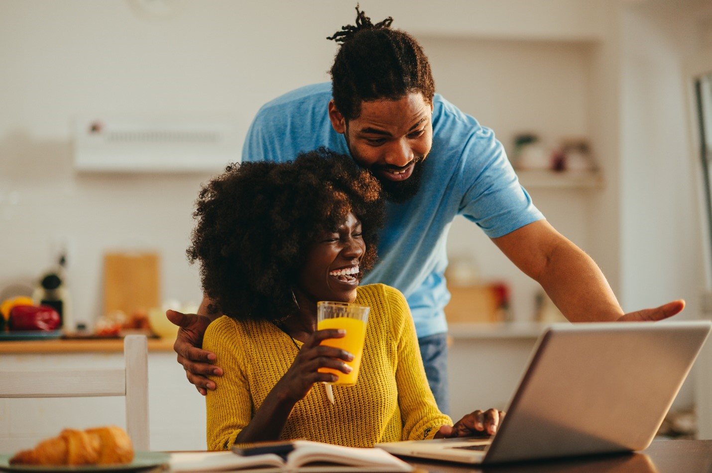 Man and woman happily discussing what's on their laptop in front of them.