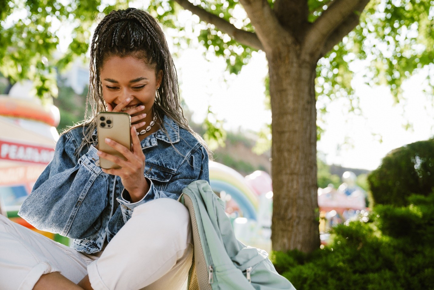 A young woman smiles down at her phone with glee.
