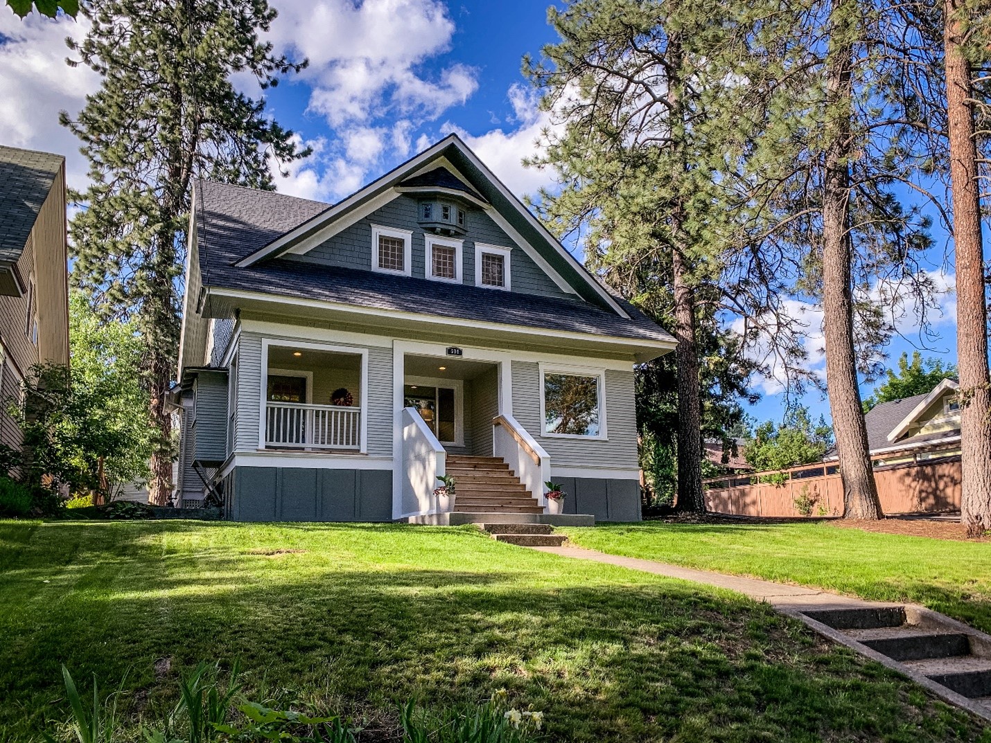 A moderately sized family home with blue-gray shingles, surrounded by pine trees.
