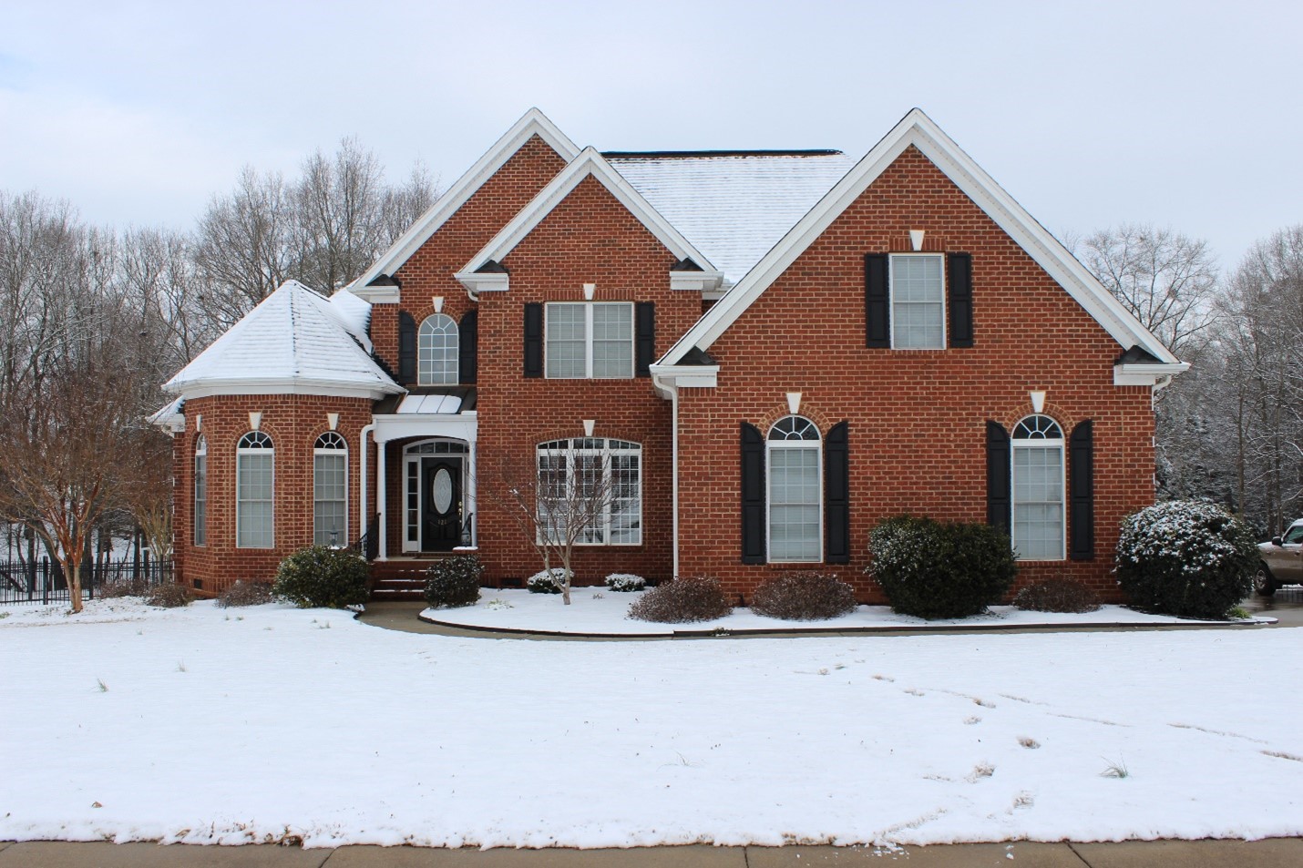 A brick home in snow with cleared pathways.